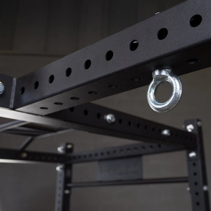A close-up view of the Body-Solid Pro ClubLine Power Rack Connecting Bar SPRACB, featuring a black metal structure with multiple holes and an attached metal ring.