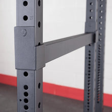 Close-up view of the Body-Solid Pro ClubLine Premium Safeties SPRSF attachment on a weight rack, showcasing the adjustable safety bars and numbered holes for customization.