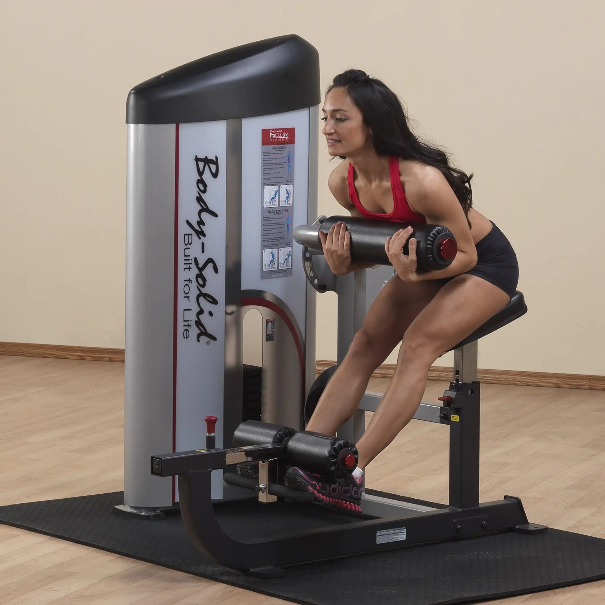 A woman using the Body-Solid Pro ClubLine Series 2 Ab & Back Machine S2ABB for a workout, demonstrating proper form while engaging in exercise.
