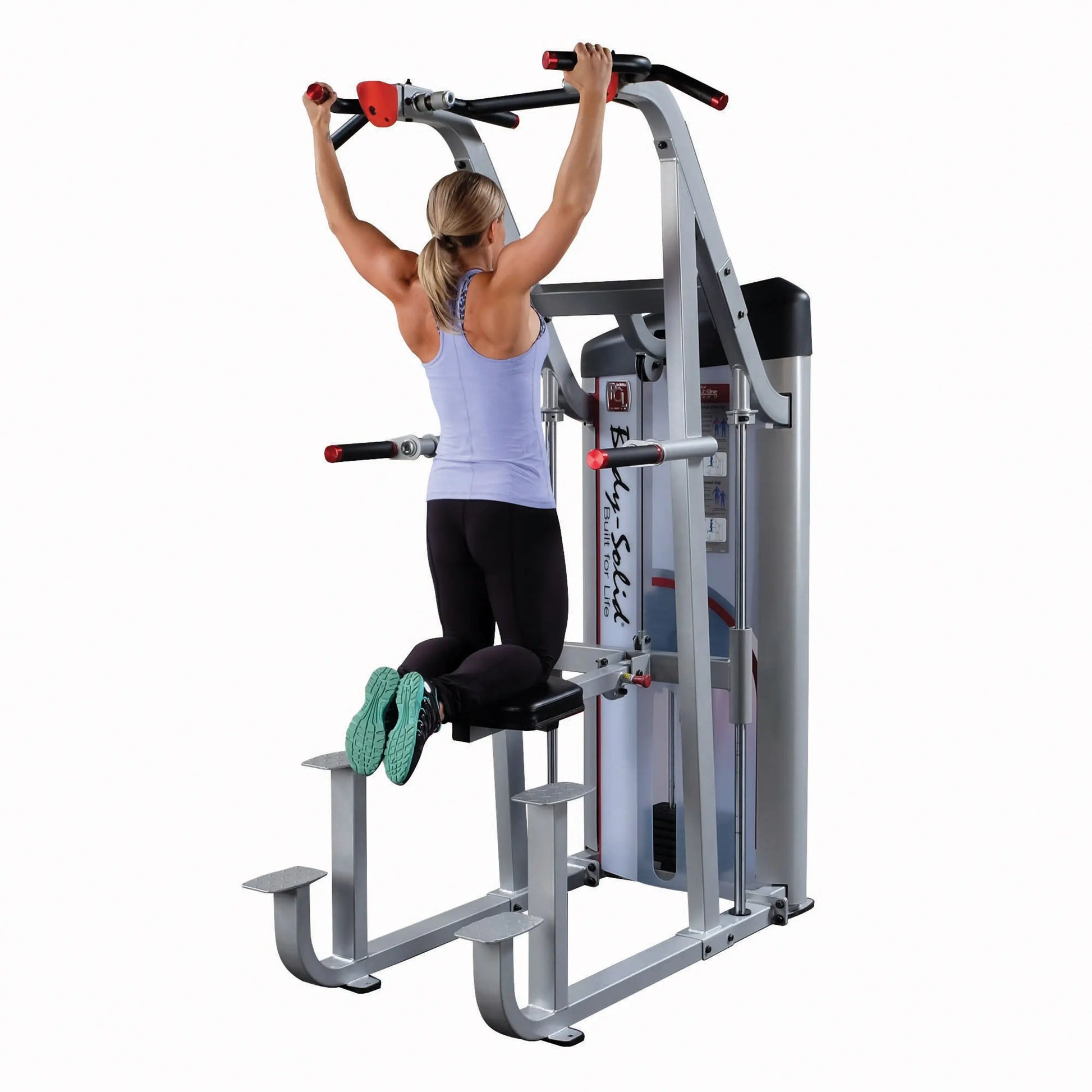 A person using the Body-Solid Pro ClubLine Series 2 Assisted Chin & Dip Machine S2ACD, demonstrating an assisted chin-up exercise while kneeling on the machine's seat.