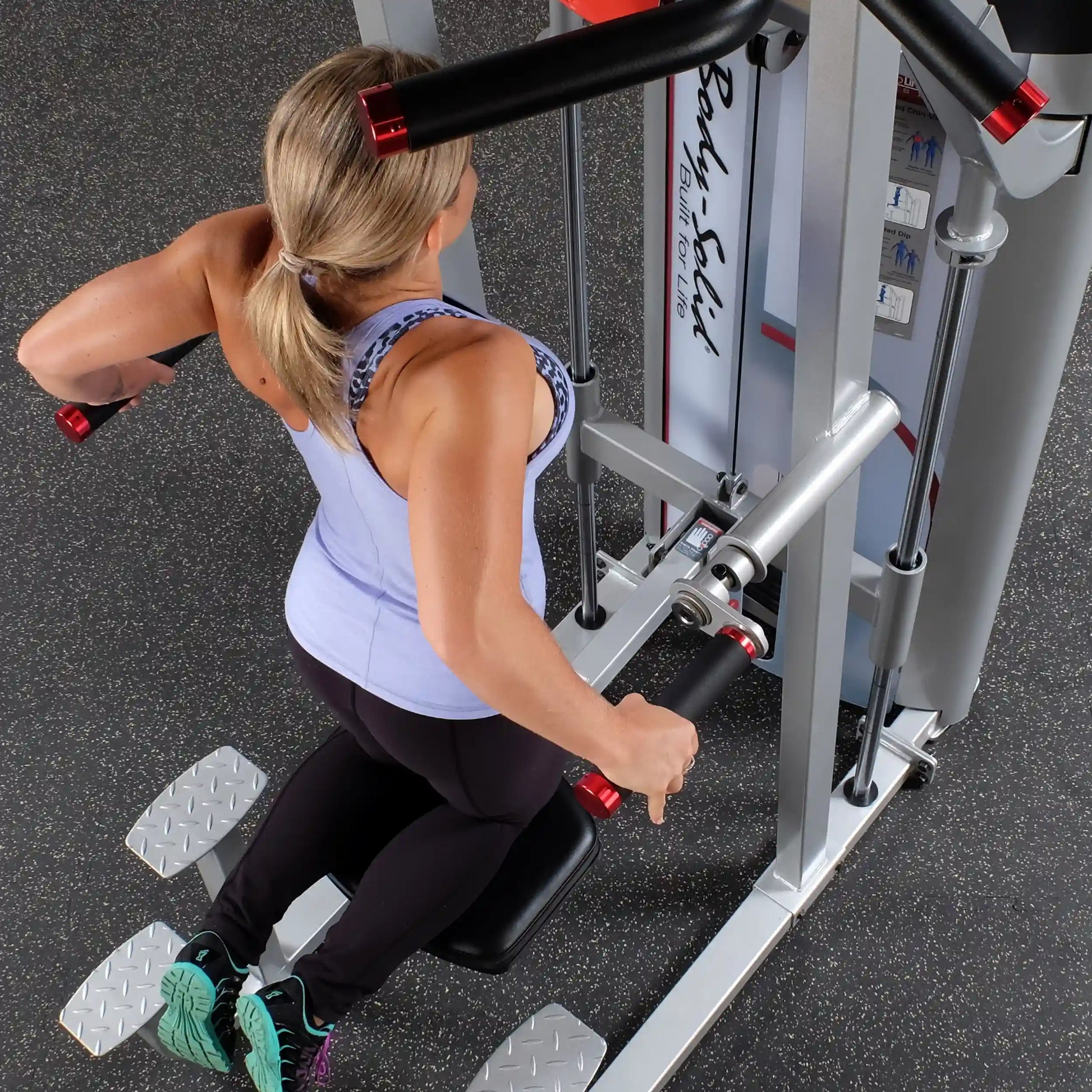 Woman using the Body-Solid Pro ClubLine Series 2 Assisted Chin & Dip Machine S2ACD, demonstrating an exercise with a focus on upper body strength.