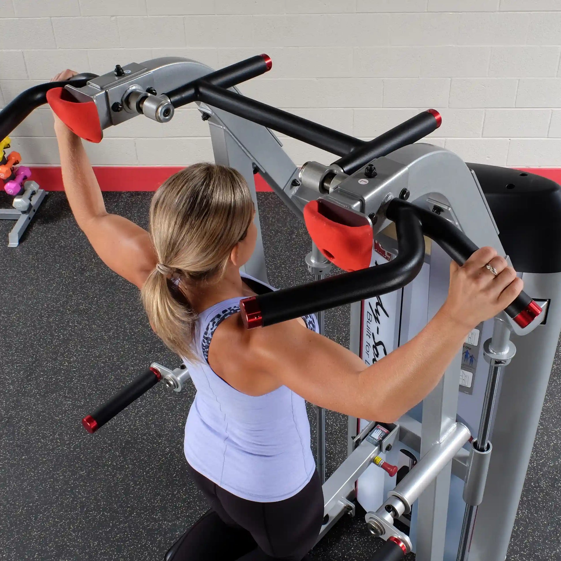 A person using the Body-Solid Pro ClubLine Series 2 Assisted Chin & Dip Machine S2ACD, demonstrating an exercise with the machine's handles.