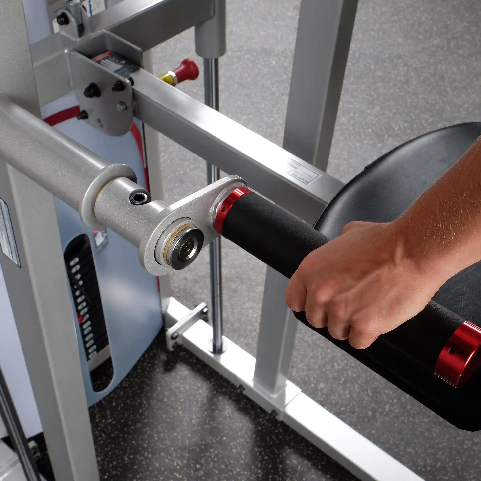 Close-up of a hand gripping the handle of the Body-Solid Pro ClubLine Series 2 Assisted Chin & Dip Machine S2ACD, showcasing its ergonomic design and features.