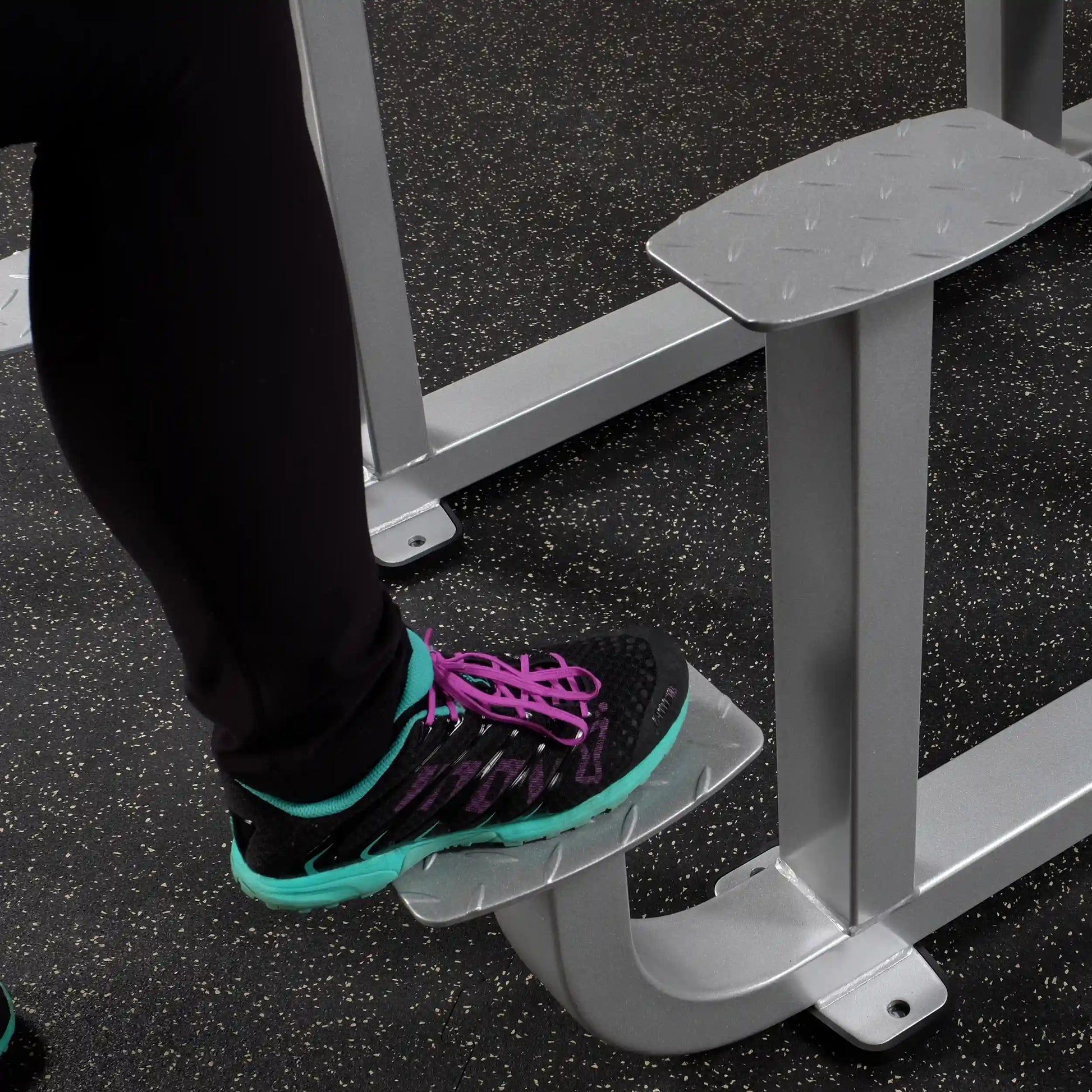 Close-up of a foot on the footrest of the Body-Solid Pro ClubLine Series 2 Assisted Chin & Dip Machine S2ACD, showcasing the gym equipment's design and functionality.
