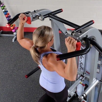 A woman using the Body-Solid Pro ClubLine Series 2 Assisted Chin & Dip Machine S2ACD in a gym setting, focusing on her upper body workout.