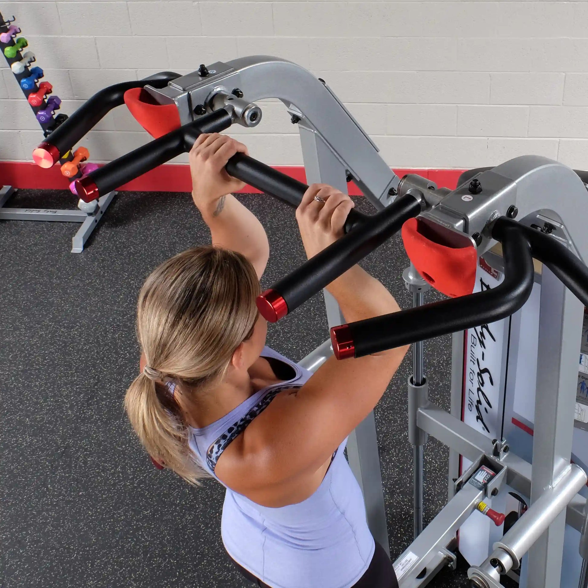 A person using the Body-Solid Pro ClubLine Series 2 Assisted Chin & Dip Machine S2ACD, demonstrating a chin-up exercise with a focus on the machine's handles and design.