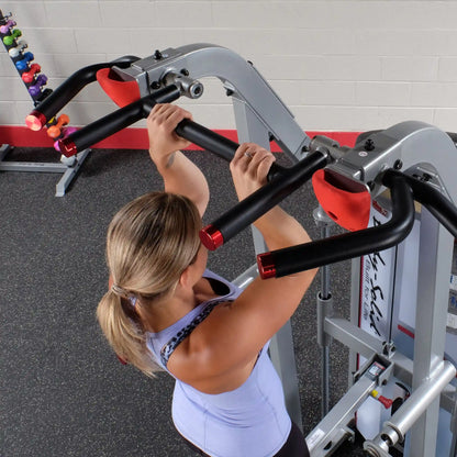 A person using the Body-Solid Pro ClubLine Series 2 Assisted Chin & Dip Machine S2ACD, demonstrating a chin-up exercise with a focus on the machine's handles and design.