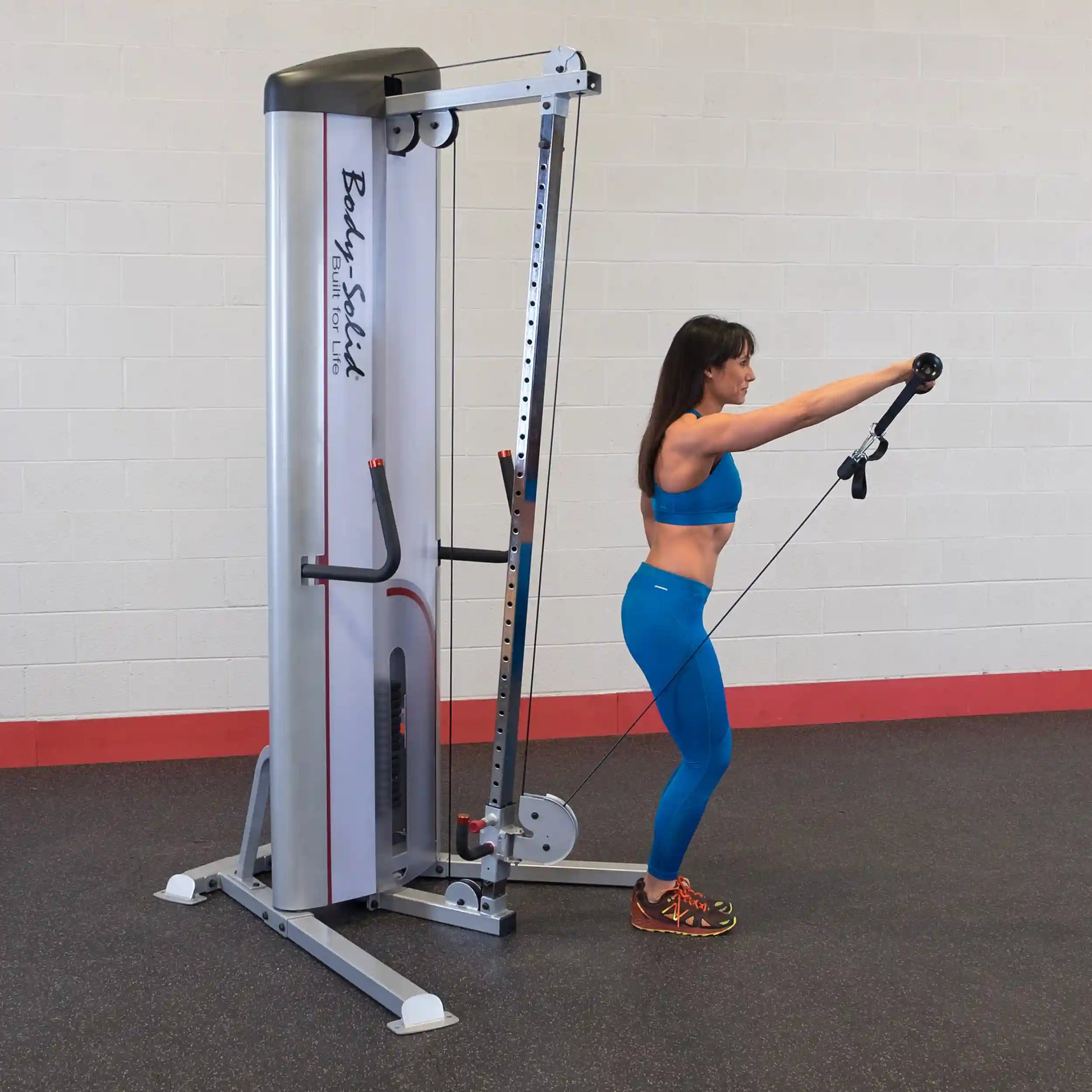 A woman in a blue workout outfit using the Body-Solid Pro ClubLine Series 2 Cable Column S2CC in a gym setting, performing an exercise with a cable attachment.