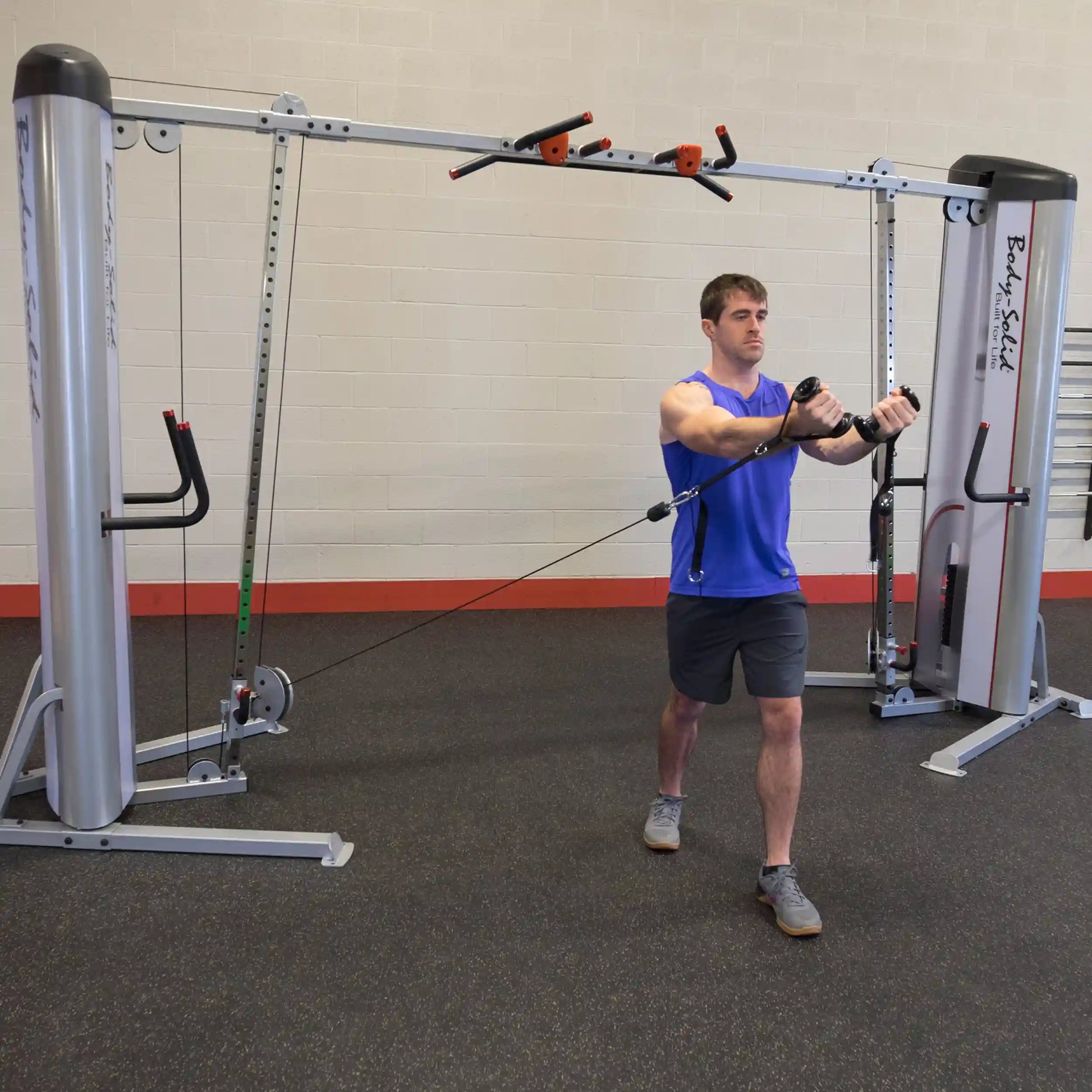 A person performing a cable crossover exercise using the Body-Solid Pro ClubLine Series 2 Cable Crossover S2CCO in a gym setting.