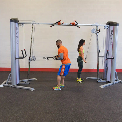 A man and a woman using the Body-Solid Pro ClubLine Series 2 Cable Crossover S2CCO in a gym setting, performing cable exercises.