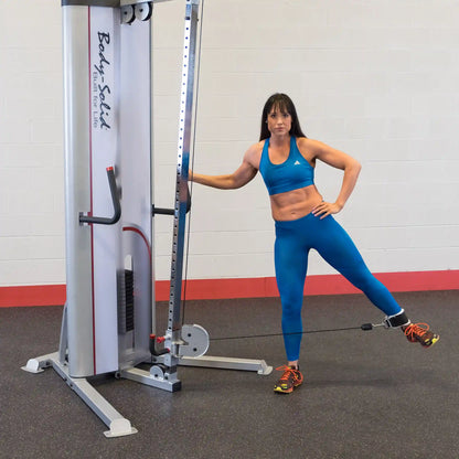 A woman in a blue workout outfit using the Body-Solid Pro ClubLine Series 2 Cable Crossover S2CCO in a gym setting, demonstrating a fitness exercise.