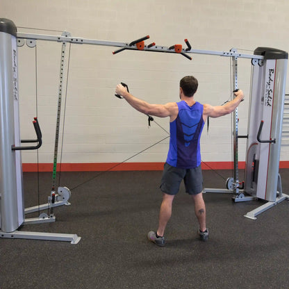 A person using the Body-Solid Pro ClubLine Series 2 Cable Crossover S2CCO, performing a cable crossover exercise in a gym setting.