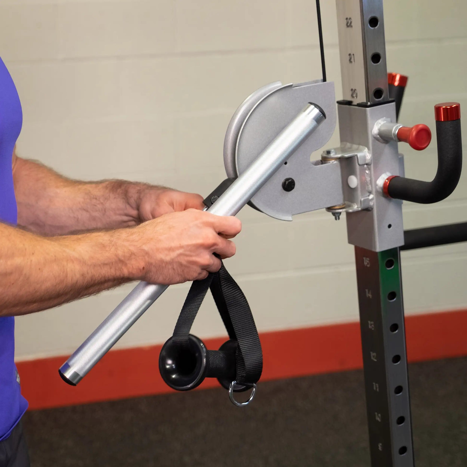 A person adjusting the Body-Solid Pro ClubLine Series 2 Cable Crossover S2CCO, focusing on the cable and attachment.