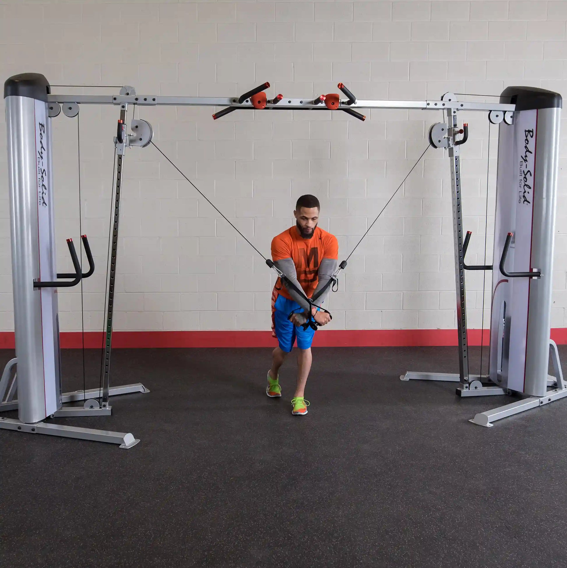 A person performing a cable crossover exercise using the Body-Solid Pro ClubLine Series 2 Cable Crossover S2CCO in a gym setting.