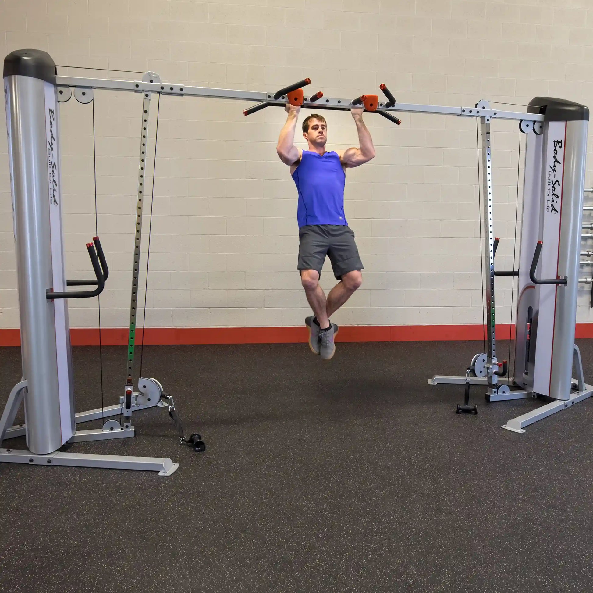 A person performing a pull-up on the Body-Solid Pro ClubLine Series 2 Cable Crossover S2CCO in a gym setting, showcasing the equipment's features and design.