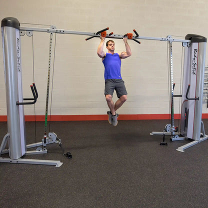 A person performing a pull-up on the Body-Solid Pro ClubLine Series 2 Cable Crossover S2CCO in a gym setting, showcasing the equipment's features and design.