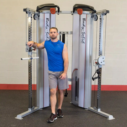 A man standing next to the Body-Solid Pro ClubLine Series 2 Functional Trainer S2FT, demonstrating its use in a gym setting.