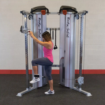 A woman performing an exercise using the Body-Solid Pro ClubLine Series 2 Functional Trainer S2FT, demonstrating a leg lift while attached to the cable machine.