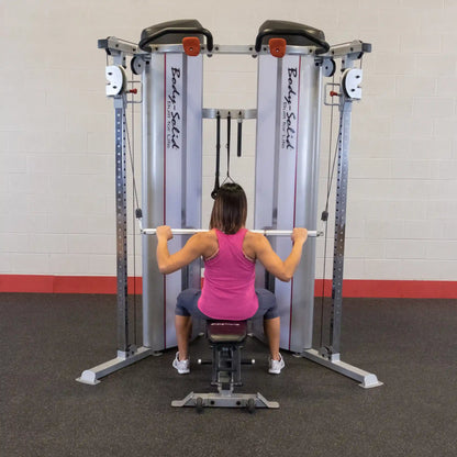 A person using the Body-Solid Pro ClubLine Series 2 Functional Trainer S2FT, seated and pulling on the handles, in a gym setting.