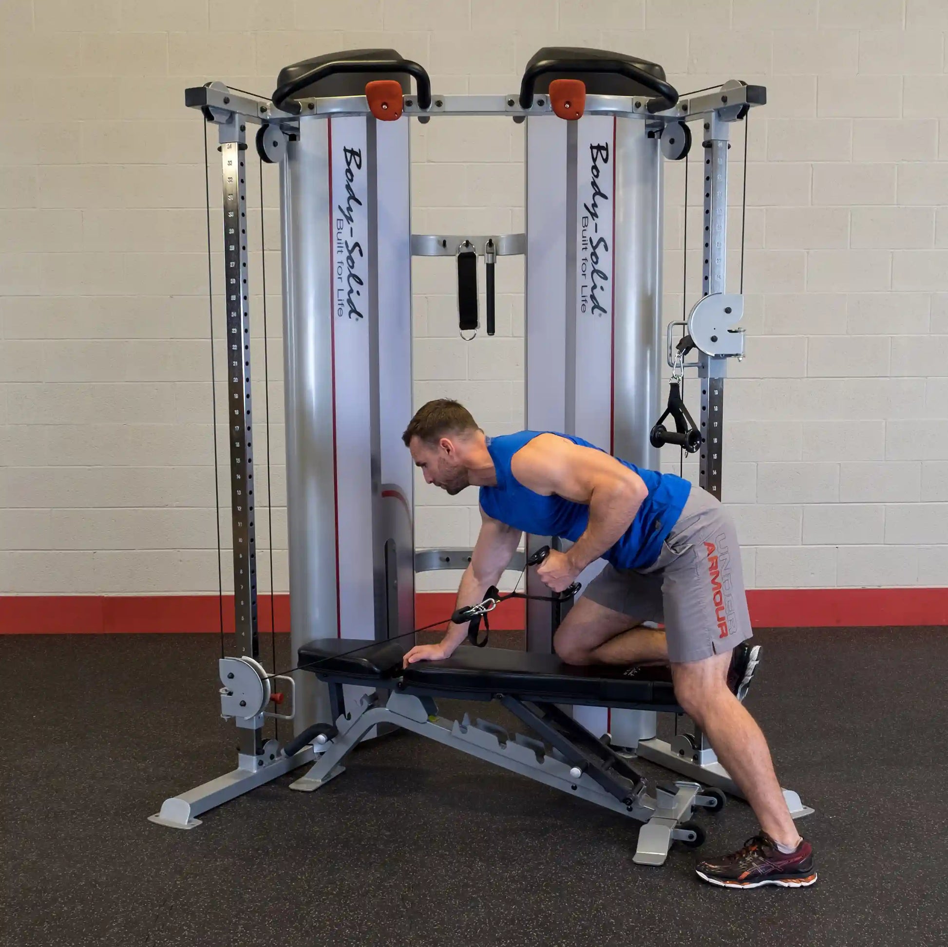 A man performing an exercise using the Body-Solid Pro ClubLine Series 2 Functional Trainer S2FT, positioned on a bench and pulling a cable attachment.