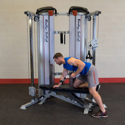 A man performing an exercise using the Body-Solid Pro ClubLine Series 2 Functional Trainer S2FT, positioned on a bench and pulling a cable attachment.