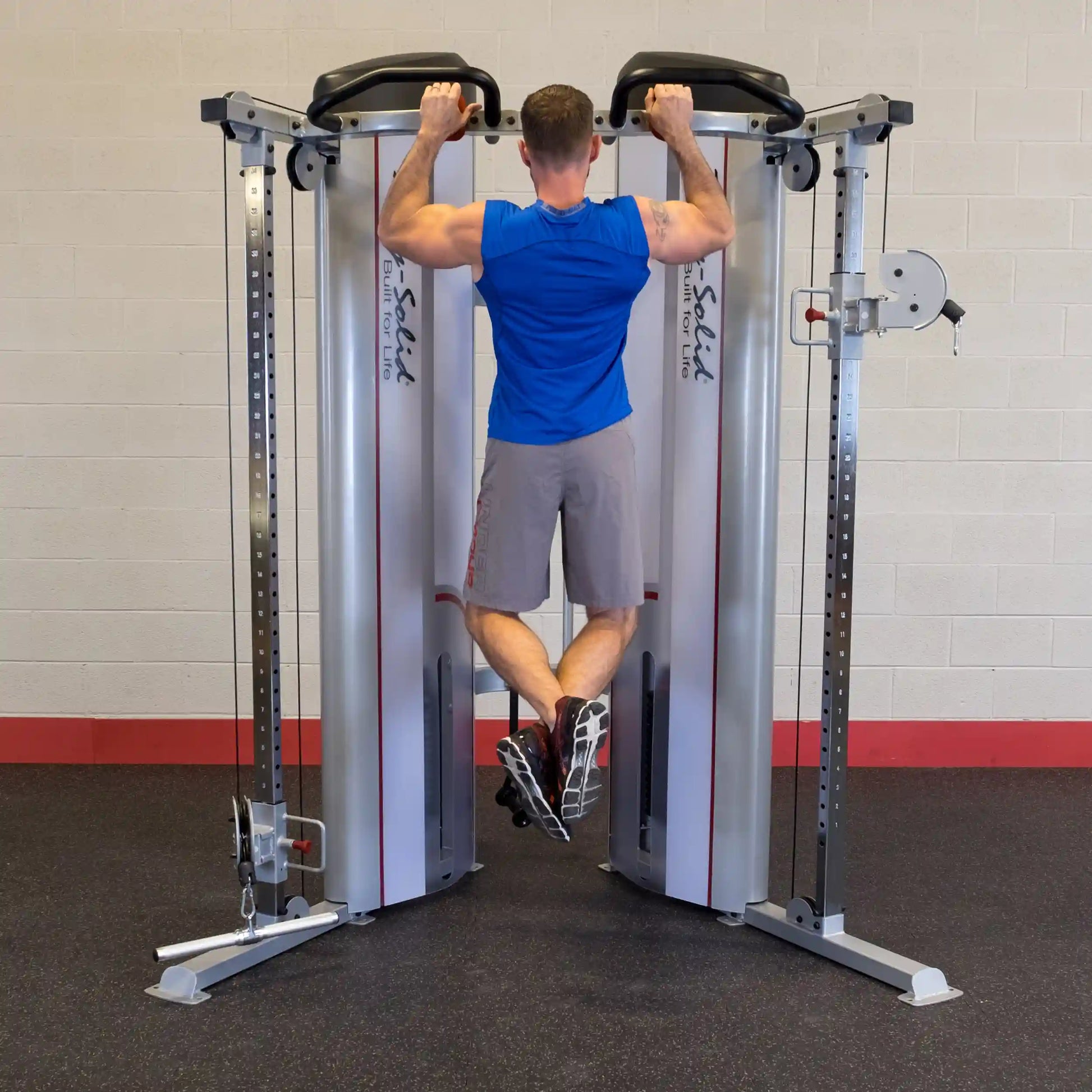 A person performing pull-ups on the Body-Solid Pro ClubLine Series 2 Functional Trainer S2FT in a gym setting, showcasing the equipment's dual cable design and sturdy build.