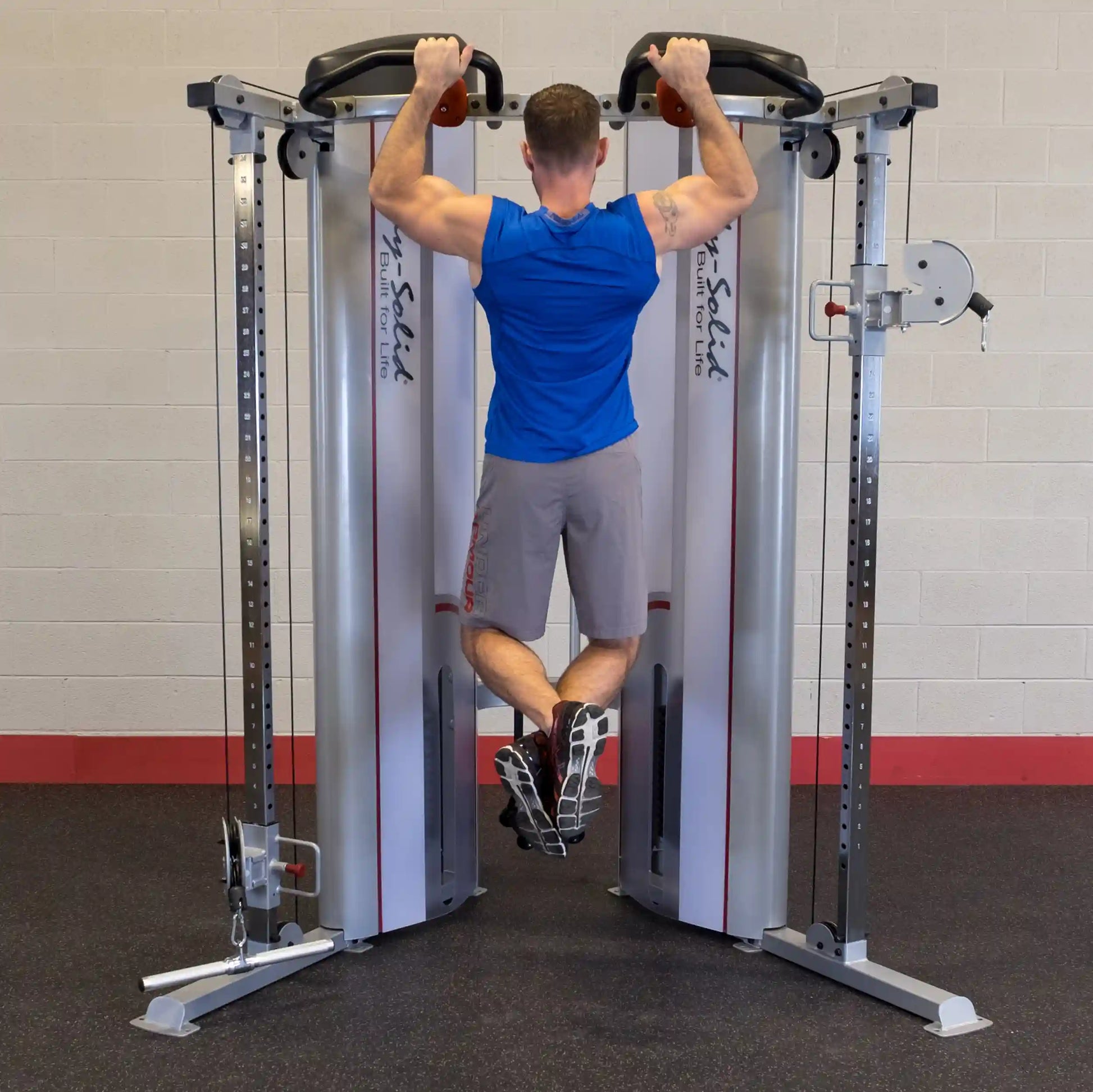 A person demonstrating an exercise on the Body-Solid Pro ClubLine Series 2 Functional Trainer S2FT, gripping the handles while performing a pull-up.