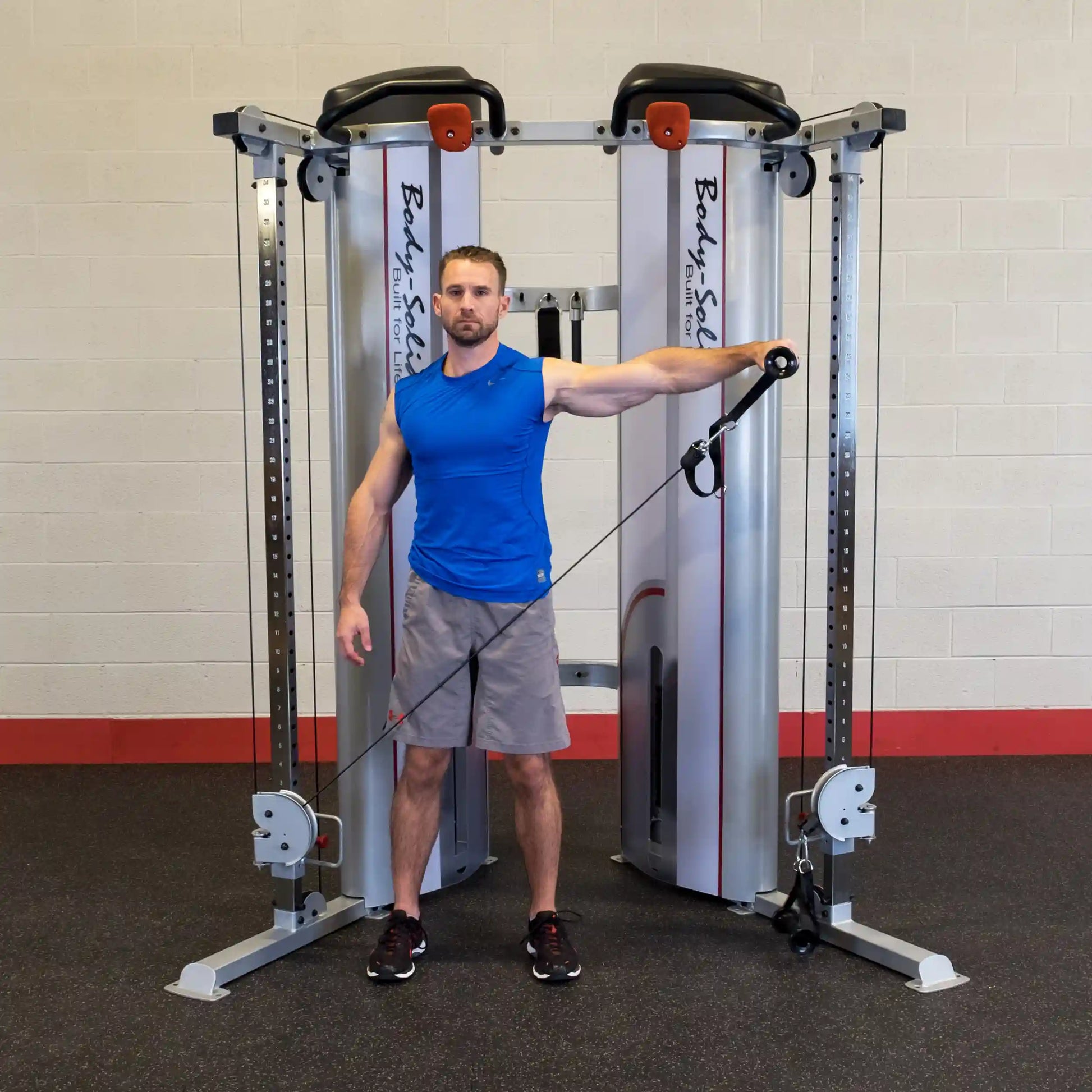 A man demonstrates an exercise using the Body-Solid Pro ClubLine Series 2 Functional Trainer S2FT, standing with one arm extended while holding a resistance cable.