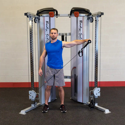 A man demonstrates an exercise using the Body-Solid Pro ClubLine Series 2 Functional Trainer S2FT, standing with one arm extended while holding a resistance cable.