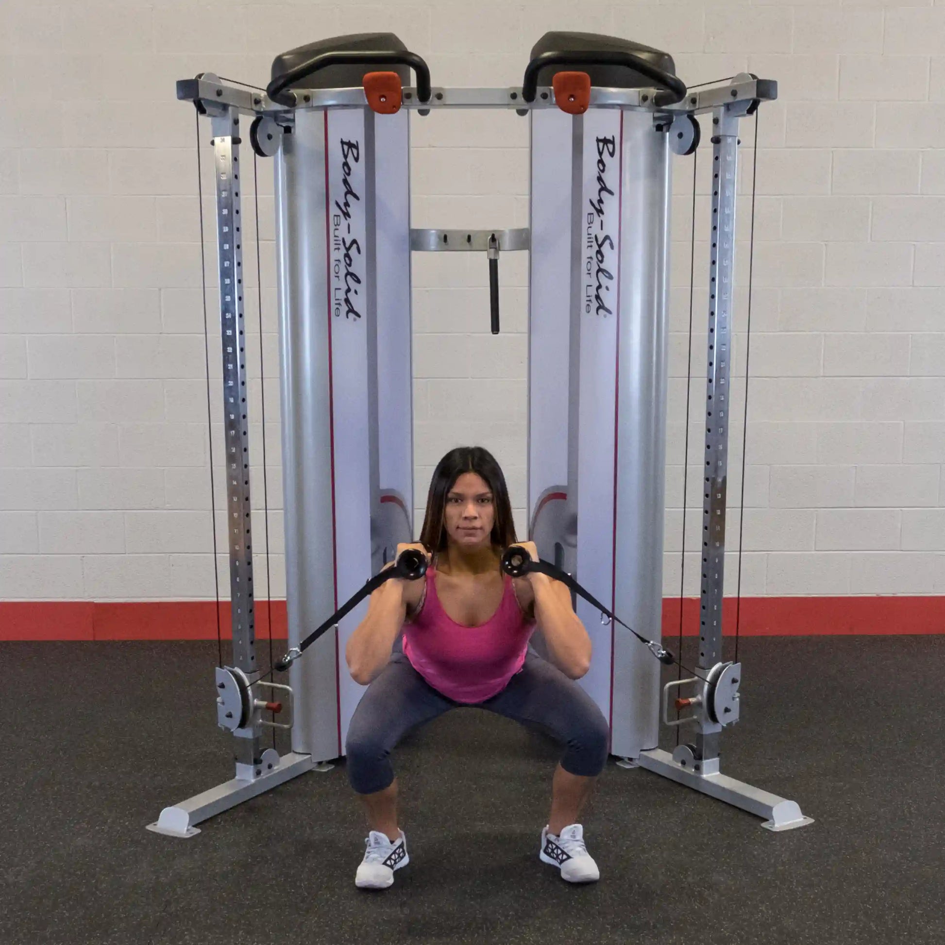 A person performing a squat using the Body-Solid Pro ClubLine Series 2 Functional Trainer S2FT, with resistance cables attached, in a gym setting.