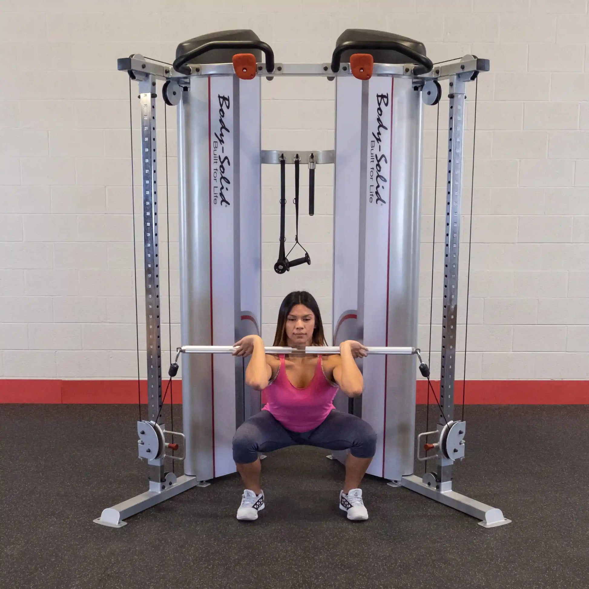 A woman performing a squat exercise using the Body-Solid Pro ClubLine Series 2 Functional Trainer S2FT in a gym setting.