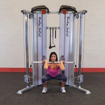 A woman performing a squat exercise using the Body-Solid Pro ClubLine Series 2 Functional Trainer S2FT in a gym setting.