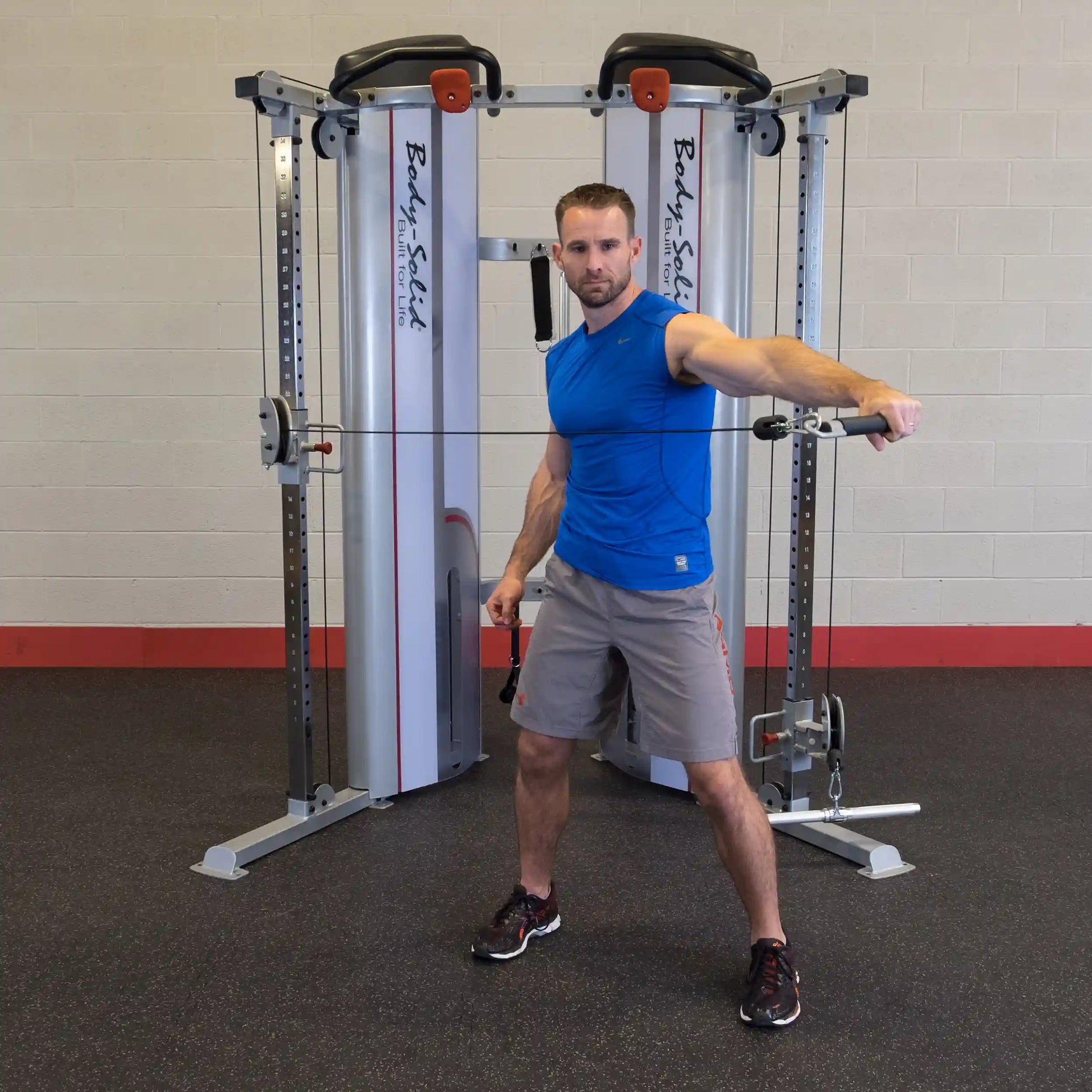 A person demonstrating an exercise using the Body-Solid Pro ClubLine Series 2 Functional Trainer S2FT, standing in a gym environment with fitness equipment in the background.