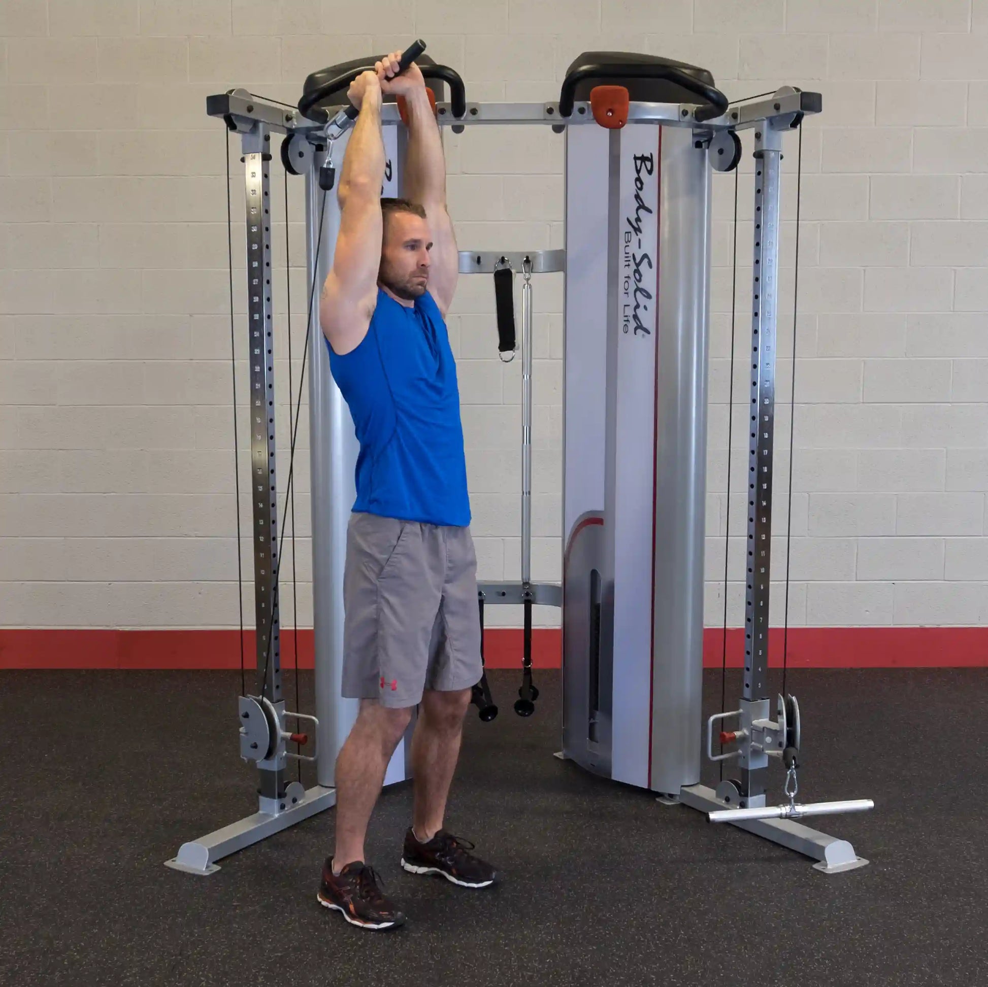 A man performing an overhead exercise using the Body-Solid Pro ClubLine Series 2 Functional Trainer S2FT in a gym setting, with a focus on strength training.
