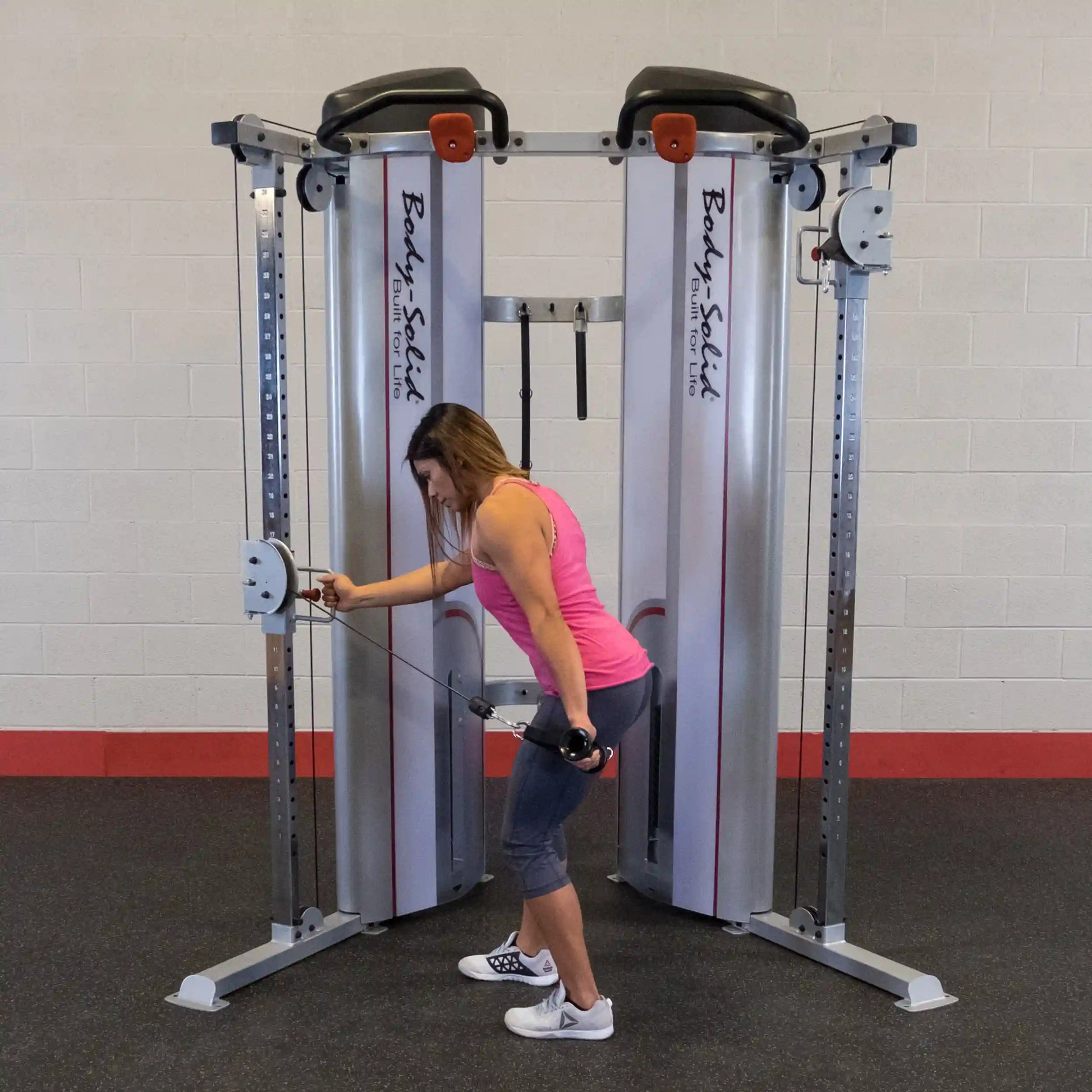 A woman performing an exercise using the Body-Solid Pro ClubLine Series 2 Functional Trainer S2FT, demonstrating proper form with cables in a gym setting.