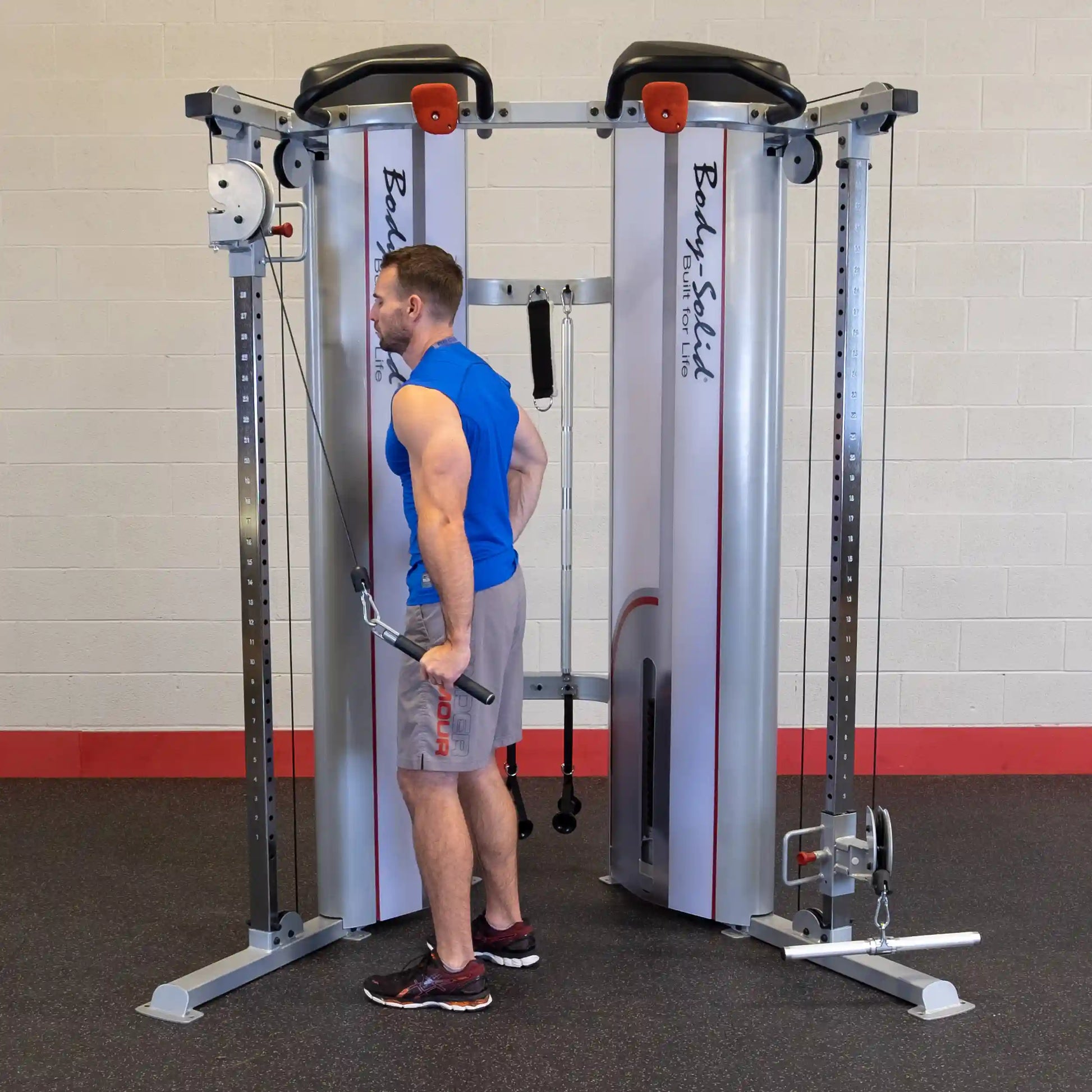 A man using the Body-Solid Pro ClubLine Series 2 Functional Trainer S2FT in a gym setting, performing an exercise with cables attached to the machine.