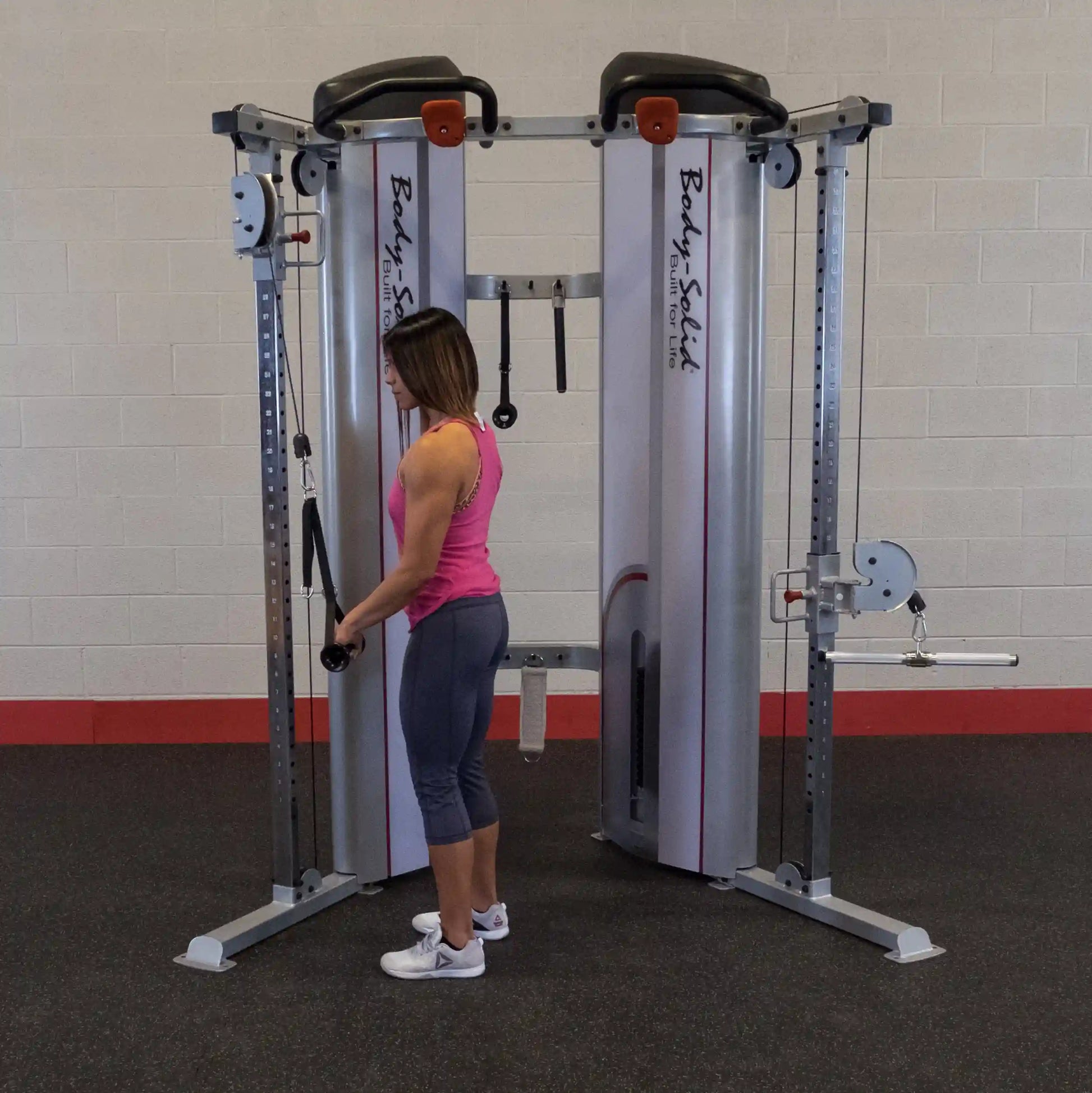 A woman using the Body-Solid Pro ClubLine Series 2 Functional Trainer S2FT in a gym setting, performing an exercise with the cable attachments.