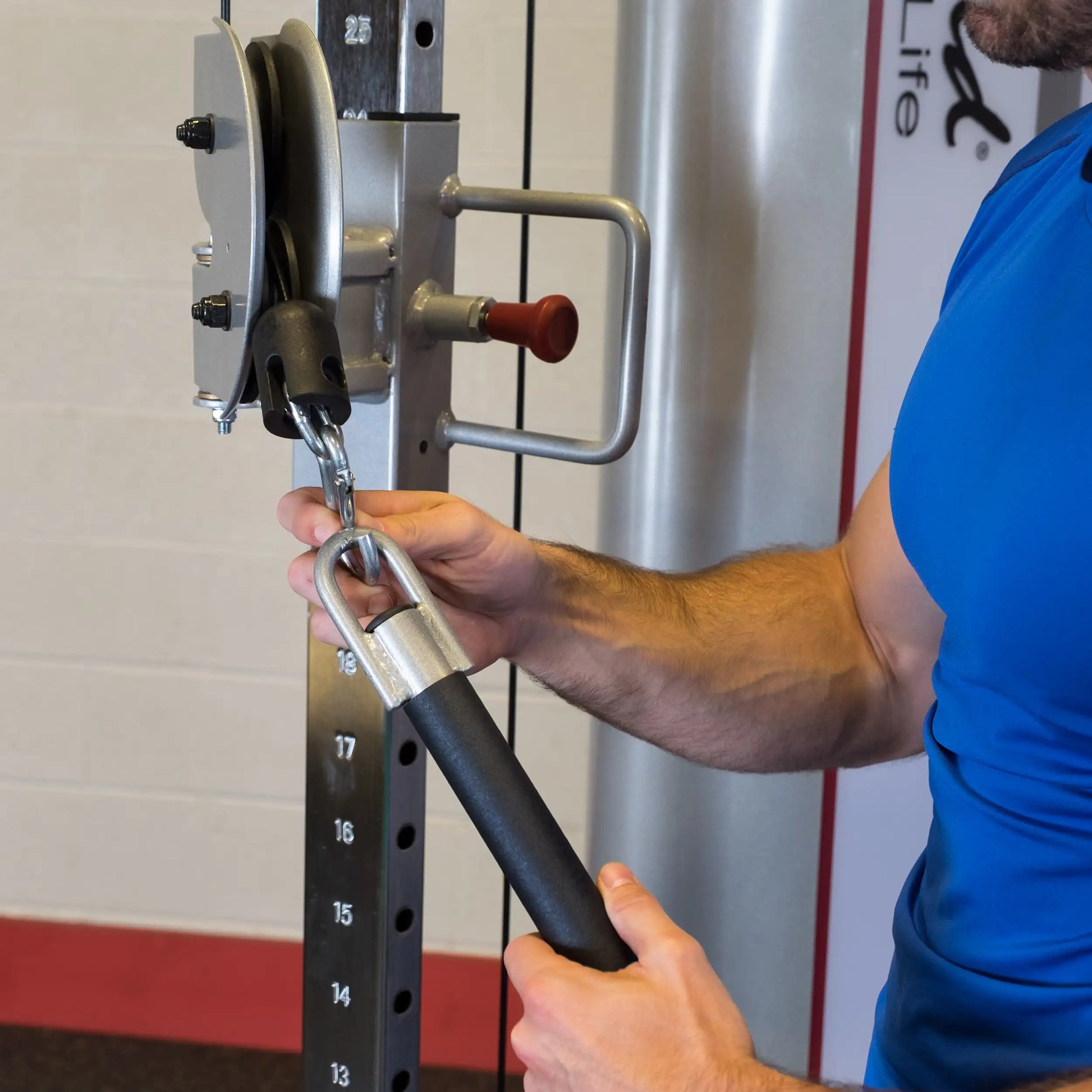 A close-up of a person using the Body-Solid Pro ClubLine Series 2 Functional Trainer S2FT, gripping a handle attached to a pulley system.