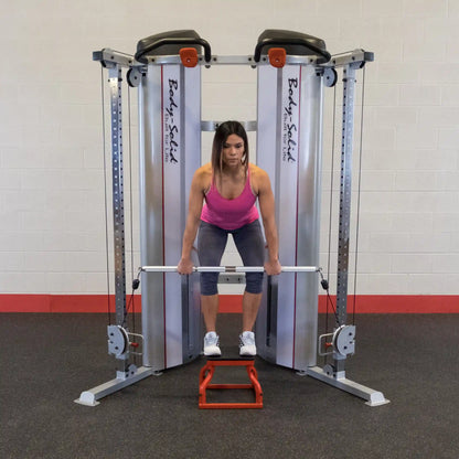 A woman performing a deadlift using the Body-Solid Pro ClubLine Series 2 Functional Trainer S2FT, standing on a red platform with a barbell in her hands.