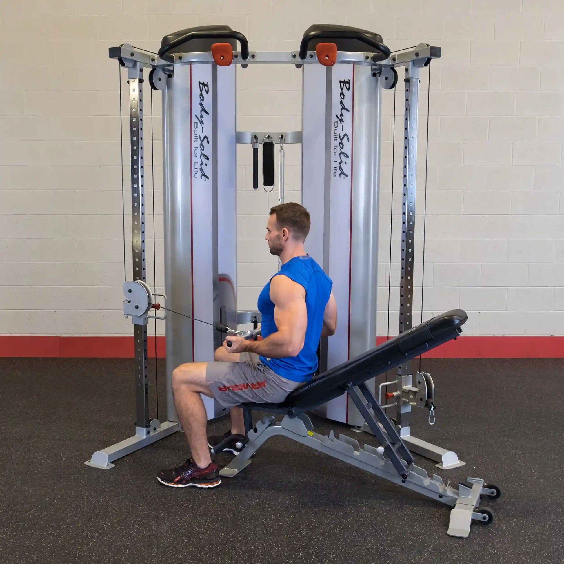 A man seated on a bench using the Body-Solid Pro ClubLine Series 2 Functional Trainer S2FT, performing a rowing exercise with a cable attachment in a gym setting.