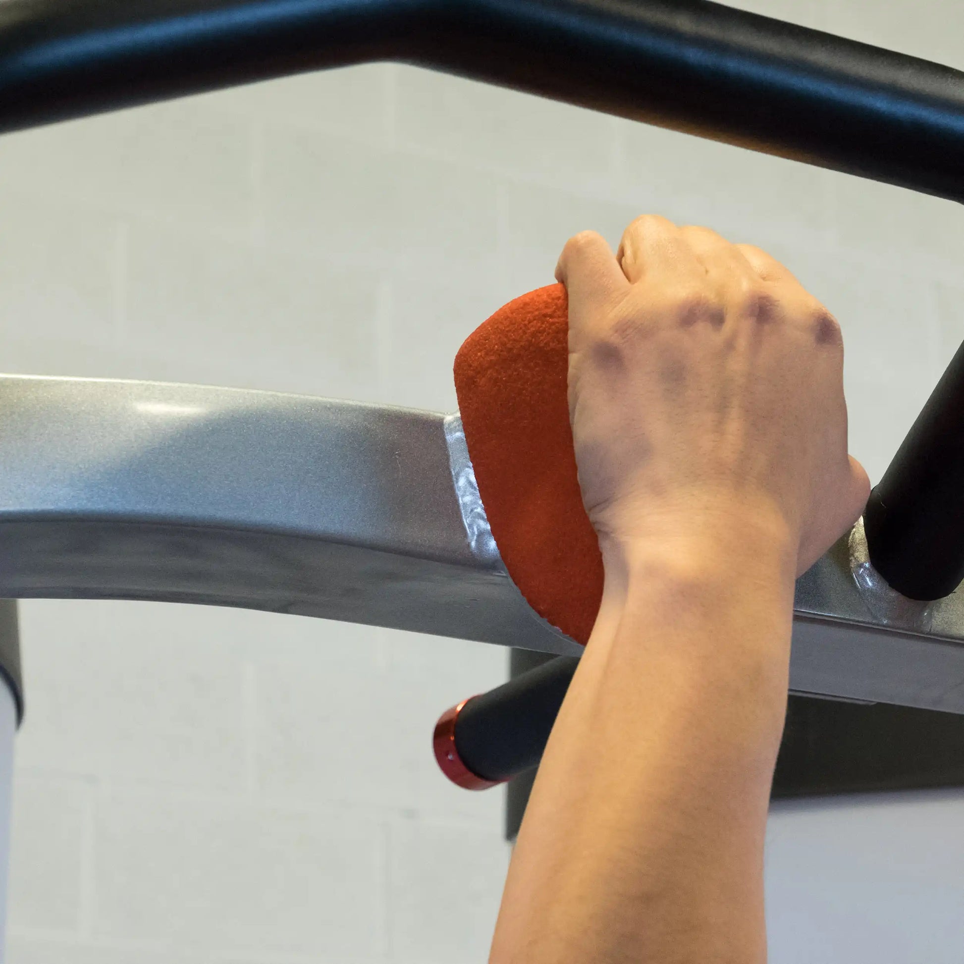 Close-up of a hand gripping the handle of the Body-Solid Pro ClubLine Series 2 Functional Trainer S2FT in a gym setting.