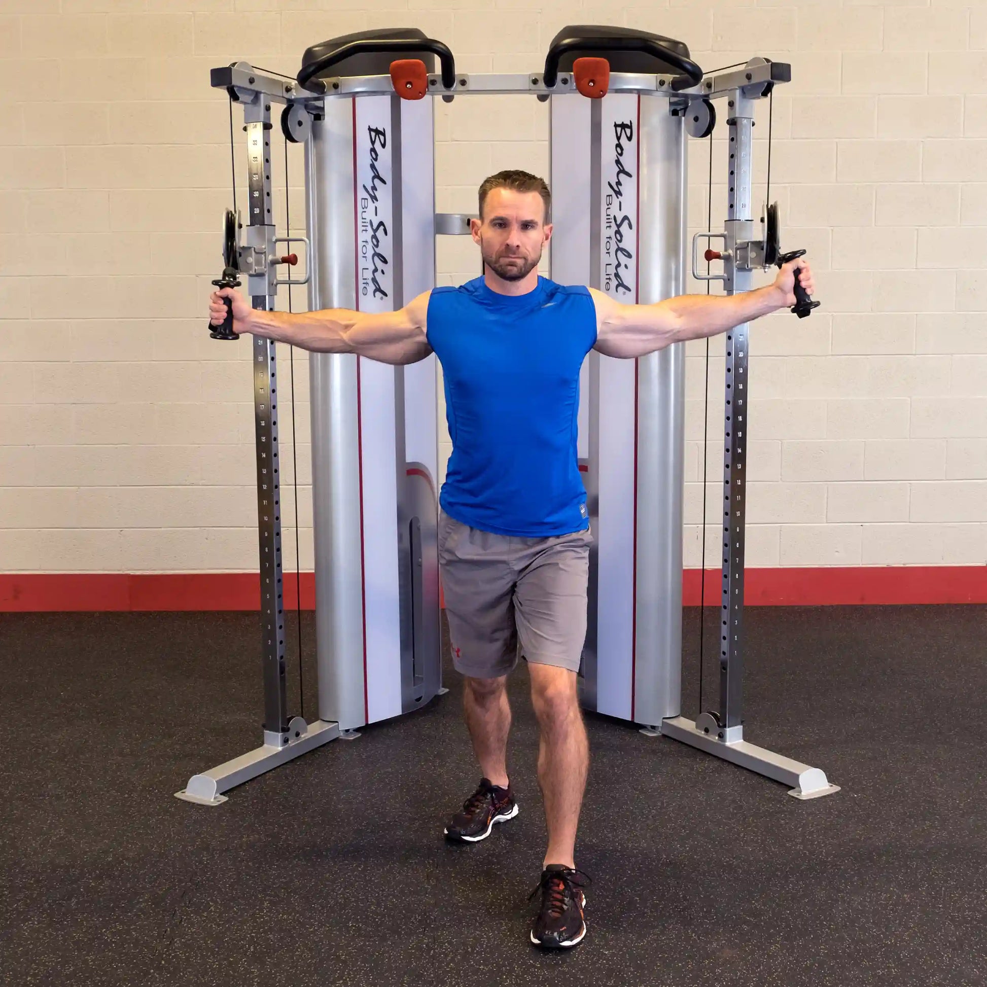 A person performing an exercise with the Body-Solid Pro ClubLine Series 2 Functional Trainer S2FT, extending arms out to the sides in a fitness studio setting.