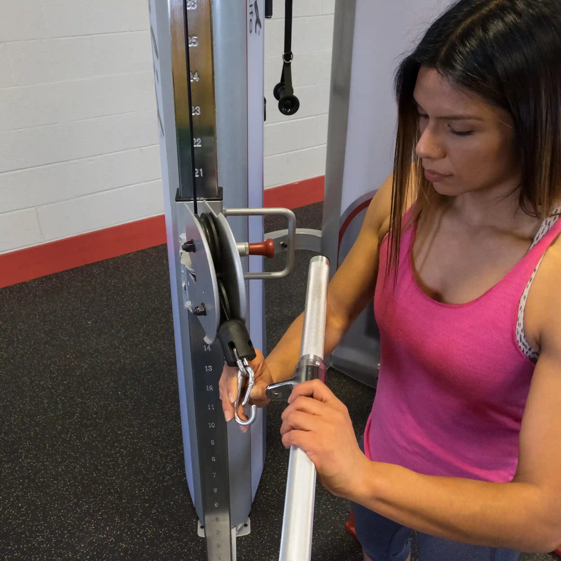 A person adjusting weights on the Body-Solid Pro ClubLine Series 2 Functional Trainer S2FT in a gym setting.