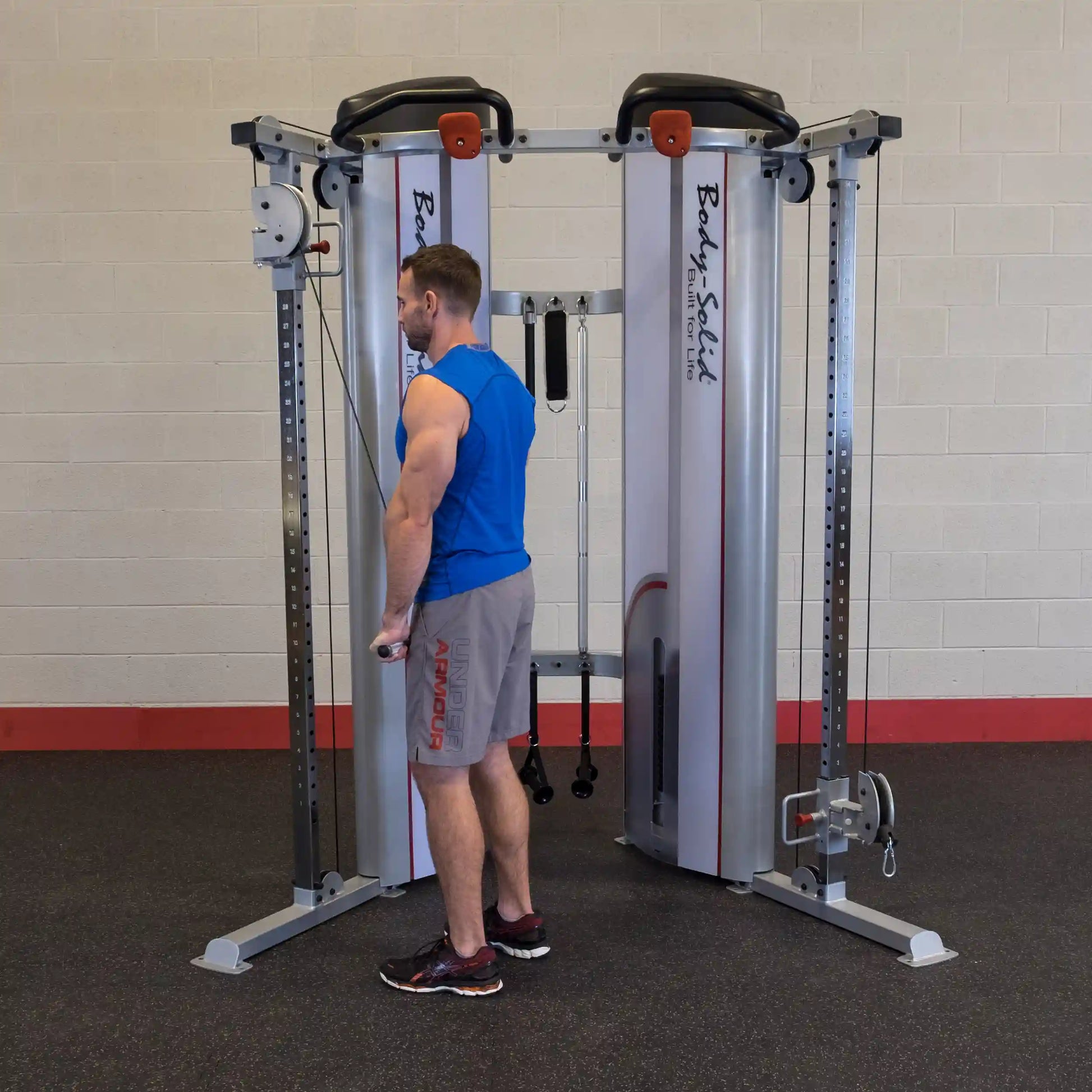 A man using the Body-Solid Pro ClubLine Series 2 Functional Trainer S2FT in a gym setting, performing a bicep curl with a cable attachment.