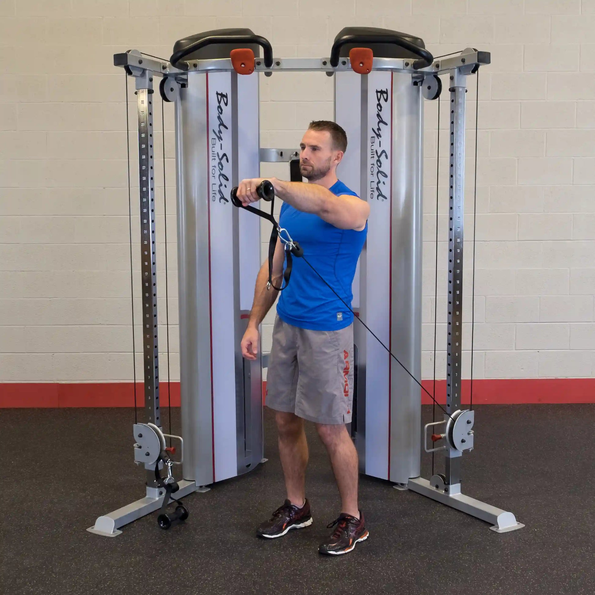 A man using the Body-Solid Pro ClubLine Series 2 Functional Trainer S2FT, performing an exercise with a cable attachment in a gym setting.