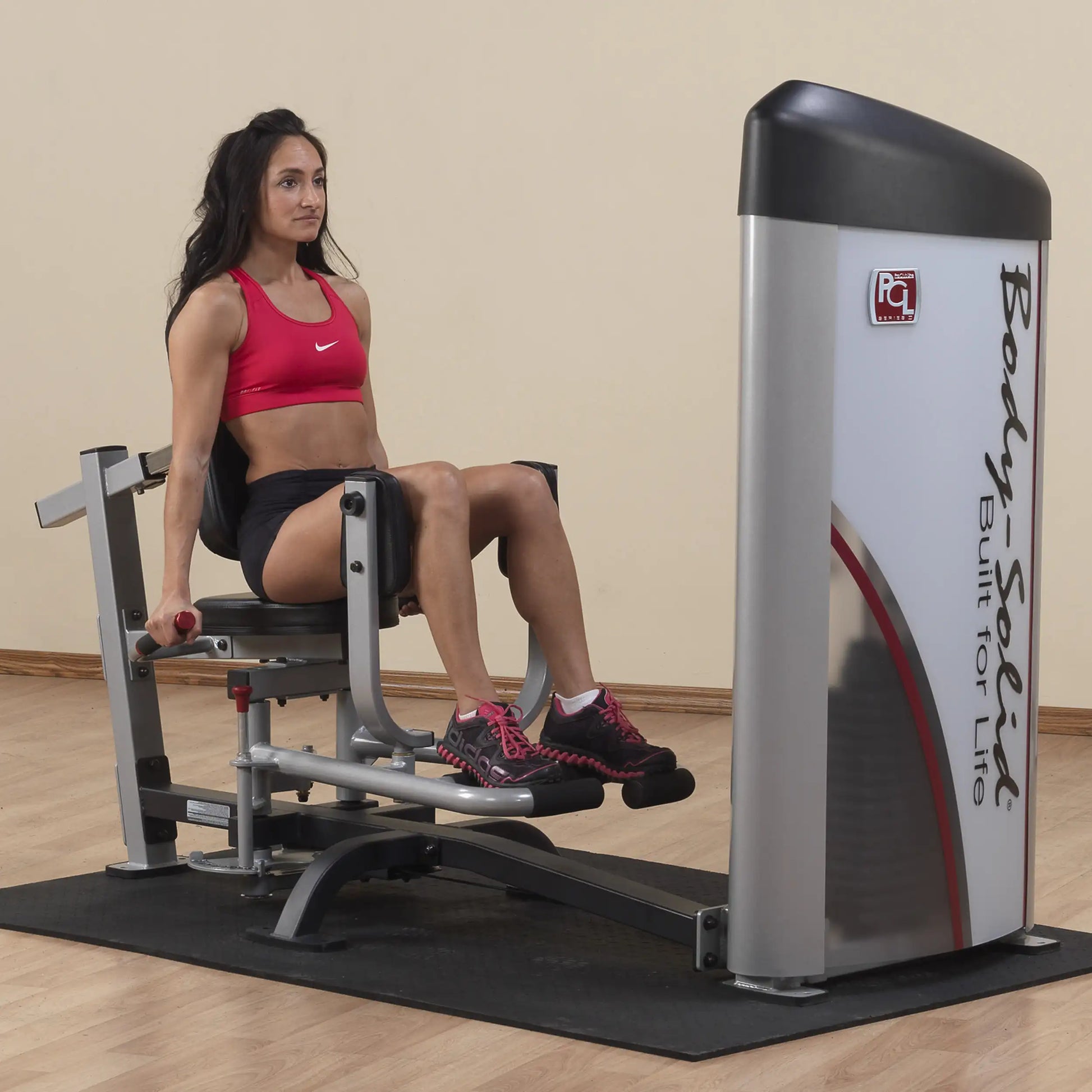 A woman using the Body-Solid Pro ClubLine Series 2 Inner & Outer Thigh Machine S2IOT in a fitness studio, demonstrating inner thigh exercises.