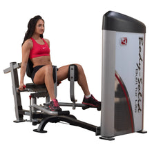 A woman demonstrating the Body-Solid Pro ClubLine Series 2 Inner & Outer Thigh Machine S2IOT, seated and engaged in a thigh workout.
