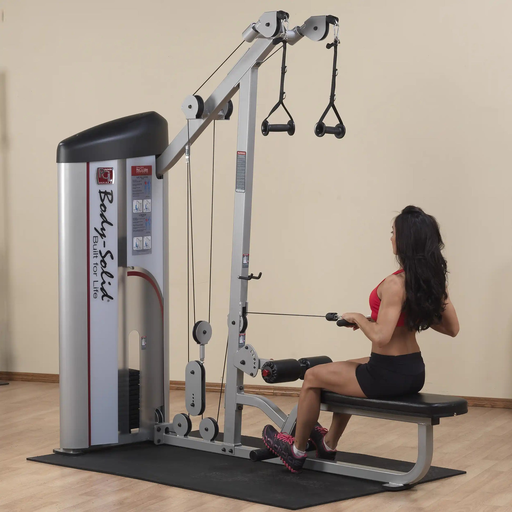 A woman using the Body-Solid Pro ClubLine Series 2 Lat Pulldown & Seated Row Machine S2LAT, performing a seated row exercise in a gym setting.