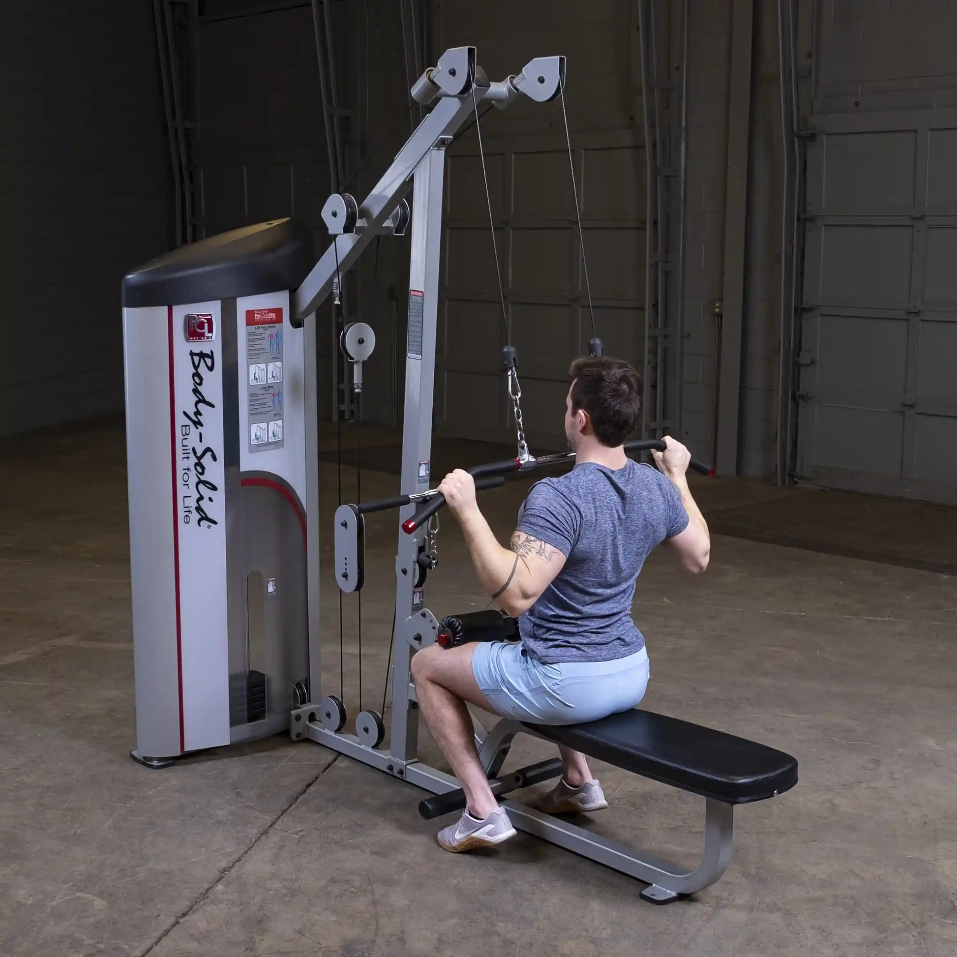 Body-Solid Pro ClubLine Series 2 Lat Pulldown & Seated Row Machine S2LAT with a person seated and performing a rowing exercise, in a gym setting.