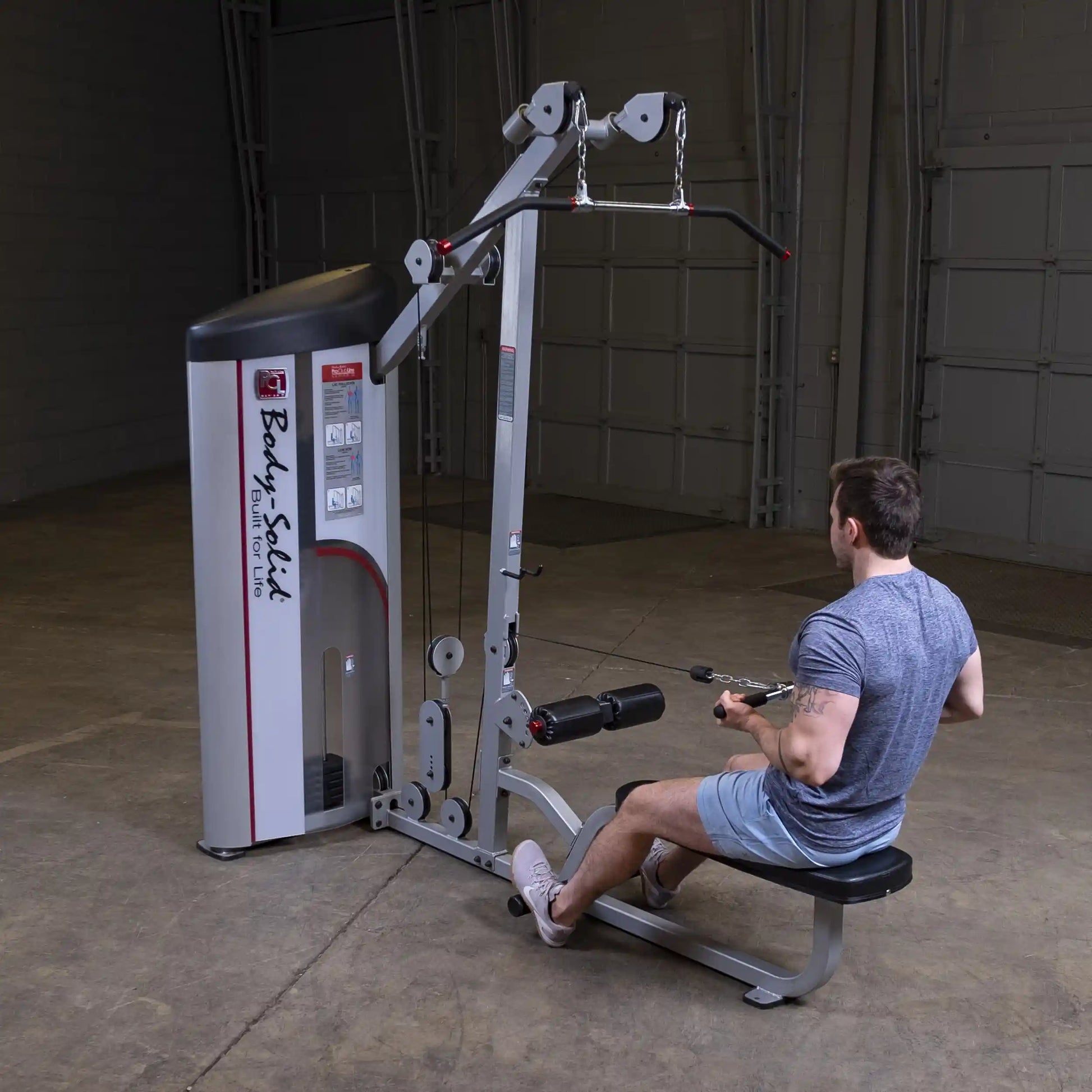 A person using the Body-Solid Pro ClubLine Series 2 Lat Pulldown & Seated Row Machine S2LAT in a gym setting.